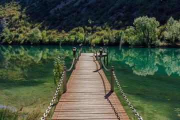 Obraz premium Wooden jetty in transparent water lake between mountains