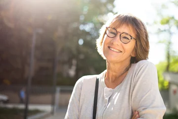 Fotobehang Close up older woman with eyeglasses smiling outside © mimagephotos