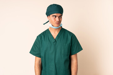 Surgeon man in blue uniform over isolated background standing and looking to the side