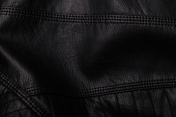 Black leather jacket texture with seams. Background or backdrop, clothing surface.
