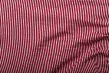 Texture of red and white striped cotton wrinkled fabric, background or backdrop. Clothing, sewing, gressmaking, haberdashery.