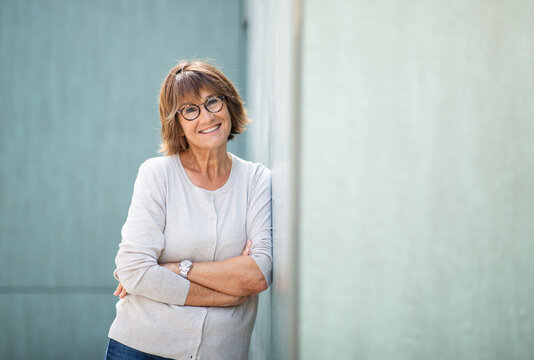 woman in 50s leaning against wall and smiling