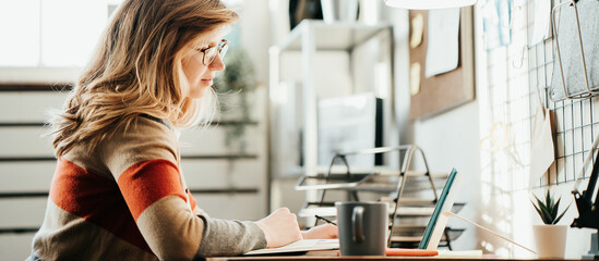Woman study at her cozy loft workplace. Remote lessons using tablet computer