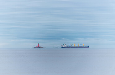 Fototapeta premium Cargo Ship on a Quiet Baltic Sea near a Lighthouse Island with Birds