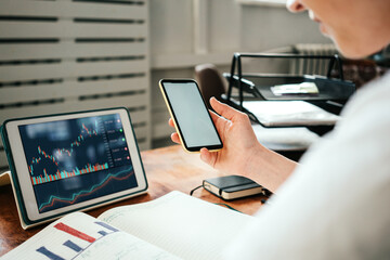 Fototapeta premium Woman working with investment stock market using tablet computer, analyzing trading data and blank phone screen in hands