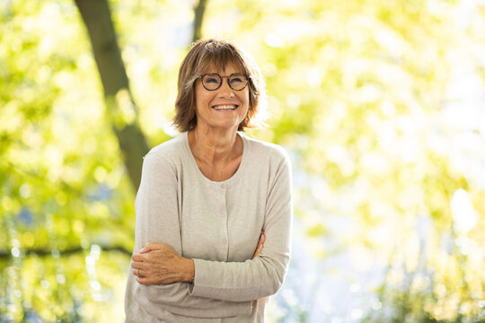 woman in 60s smiling outside in park
