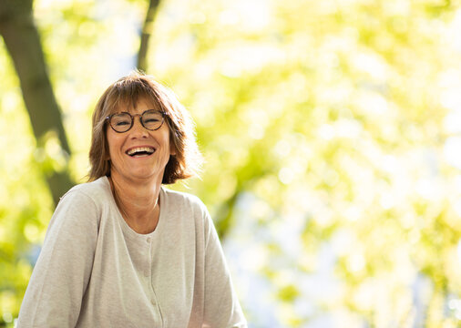 carefree older woman with glasses laughing outdoors