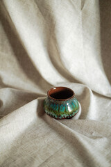 Colorful handmade ceramic pot on grey linen cloth.