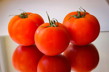 Several red tomatoes on a mirror surface