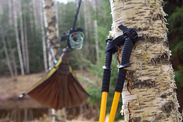 camping and trekking background. Yellow trekking sticks, Nordic walking, with a hammock setup on the background. Hiking and travel concept