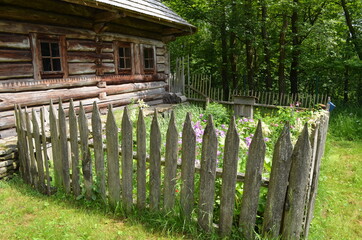 Przed starym drewnianym domem płot ze sztachet