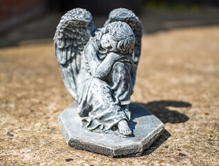 Fototapeta premium Close and selective focus of an angel statuette in a private back yard with intentional shallow depth of field and bokeh