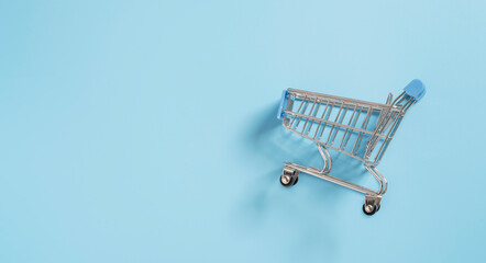 Small shopping cart trolley on blue background for online shopping and e-commerce concept.