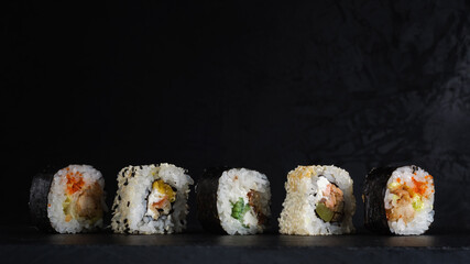 fresh sushi in a row on a stone board on a dark plaster background. artistic moody food photo with copy space