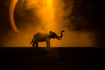 Silhouette of an elephant miniature standing at foggy night. Creative table decoration with...