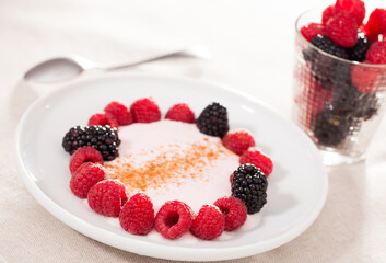 breakfast of raspberries and blackberries with yogurt on table