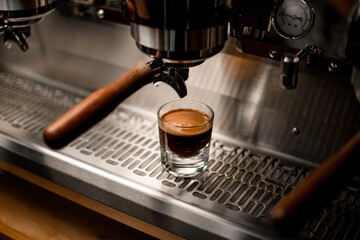 view on glass with coffee on steel surface of professional coffee machine
