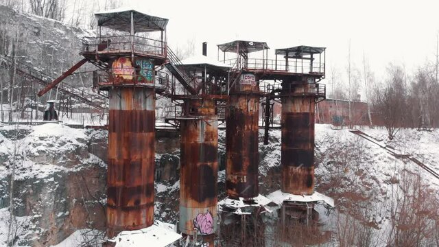 From low to top angle View of Kamieniolom Liban - A historic site where prisoners were kept during Second World War. Old machines and piping equipment. Light snow-fall. Grove of trees in the