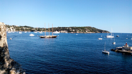Fototapeta na wymiar Boats in harbor. Beautiful panoramic landscape of Villefranche-sur-mer on a sunny day. Wonderful trip to the Cote d'Azur in France. Scenic harbour view of city of sea country. Saint Jean cap Ferrat