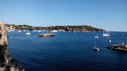 Fototapeta na wymiar Boats in harbor. Beautiful panoramic landscape of Villefranche-sur-mer on a sunny day. Wonderful trip to the Cote d'Azur in France. Scenic harbour view of city of sea country. Saint Jean cap Ferrat