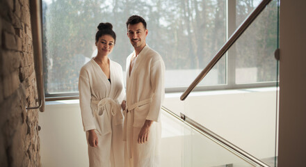 Portrait of young couple in spa resort, looking at camera on staircase.