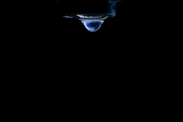 Gota a punto de caer desde grifo.