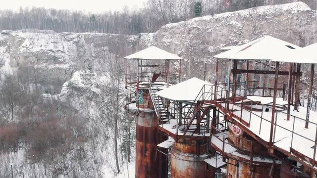 Aerial View of Kamieniolom Liban - A historic site where prisoners were kept during Second World War. Old machines and piping equipment. Light snow-fall. Grove of trees in the snowy landscape. 