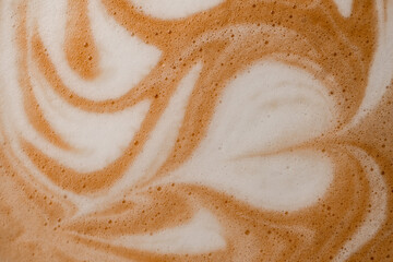 close-up of wonderful white milk patterns on brown foam of coffee drink.