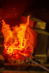 Fototapeta premium The metal spiral is heated to red in the forge in the forge during forging. Handicraft concept