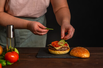 Close-up on the preparation of a magnificent burger.  Gastronomy, recipes, menus, fast food. Juicy hamburger