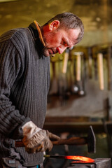 A blacksmith forging a red-hot iron billet on an anvil with a hammer. Handicraft concept