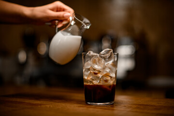 transparent glass with coffee and ice cubes on wooden table.
