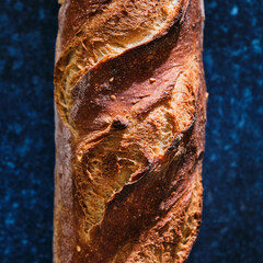 Close-up of a freshly baked baguette on a dark background. Food background.