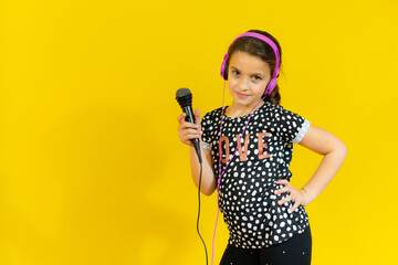 little pretty child listening music in headphones and singing isolated over yellow background