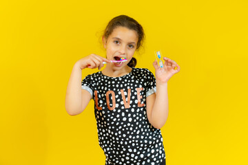 Cute little girl brushing teeth, isolated over yellow background