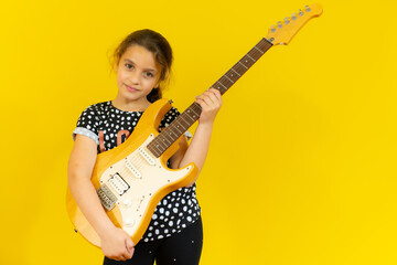 Little girl playing guitar over yellow background