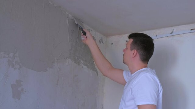 Plasterer man spackling wall with putty plaster aligning wall with spatula. Finishing construction renovation works in apartment. Worker builder making overhaul applying plaster on wall using trowel.