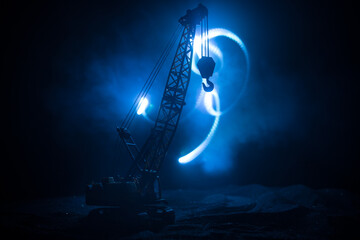 Abstract Industrial background with construction crane silhouette over amazing night sky with fog and backlight. Tower crane against the foggy sky at night.