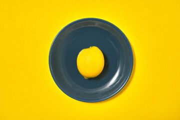 one yellow lemon on blue plate. copy space
