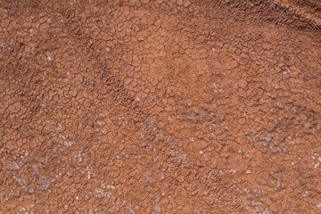 Fototapeta na wymiar The texture of dry earth is red. View from above.