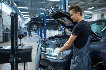 Male mechanic adjusts the headlights, car service