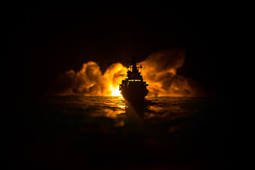 Silhouettes of a crowd standing at blurred military war ship on foggy background. Selective focus.