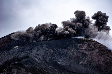 Closeup shot of the famous Etna volcano smoky and ashy top under a cloudy sky in Sicily, Italy