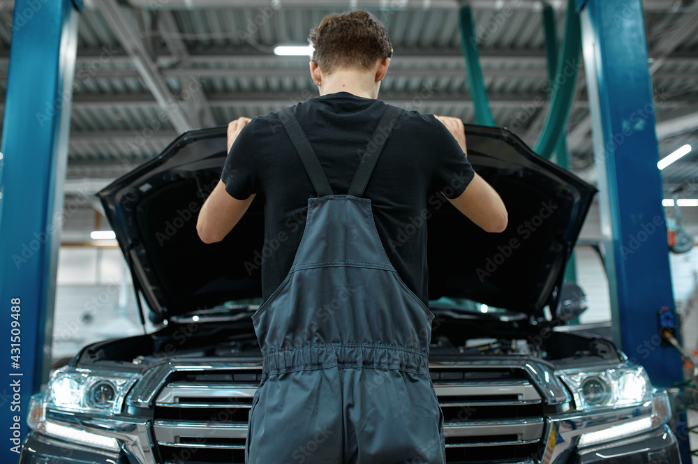 Wall mural Mechanic at opened hood, bottom view, car service