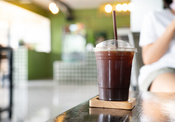 Ice americano coffee and a female customer, taking photo, on the background at cafe.