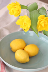 Conceptual photo. Yellow lemons and yellow tulips on the table. Kitchen Photos. Interior