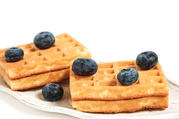Waffles and blueberries on plate on white background, isolate.