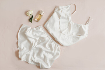Women silk lingerie on beige background top view, flatlay. Female lace nightwear clothes