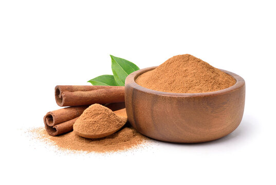 Aromatic cinnamon powder in wooden bowl with sticks on white background.