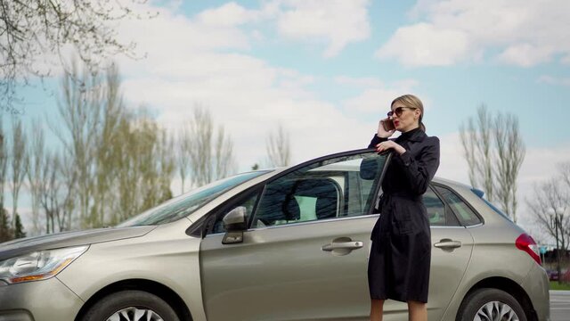 A Business Woman Discusses Business Issues On The Phone, After The End Of The Conversation She Gets Behind The Wheel Of Her Car.